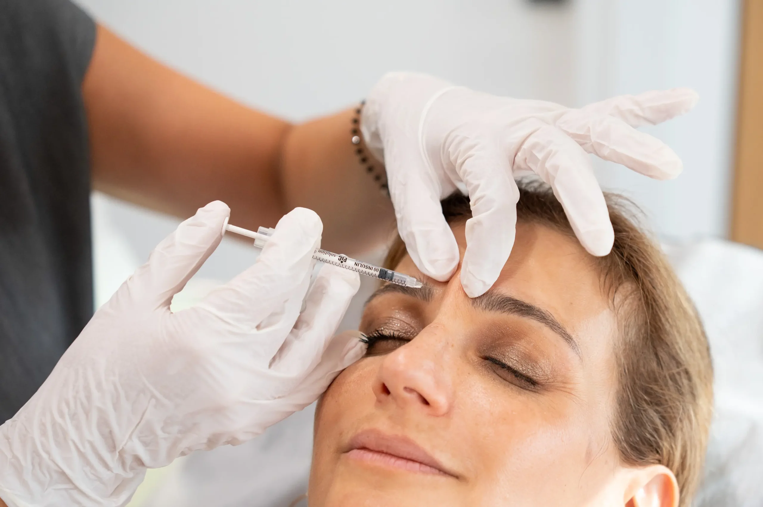 Επαγγελματίας υγείας με γάντια κάνει μια ένεση στο μέτωπο μιας γυναίκας.